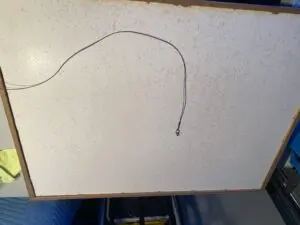 A piece of paper with a wire hanging from it.