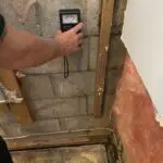 A person measuring the wall height of a bathroom.