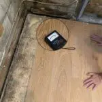 A person is standing on the floor in front of a meter.