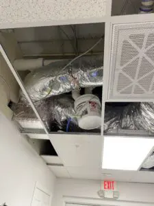 A ceiling with duct work and air conditioning units.
