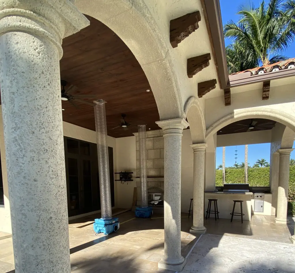 A view of an outdoor area with pillars and a kitchen.