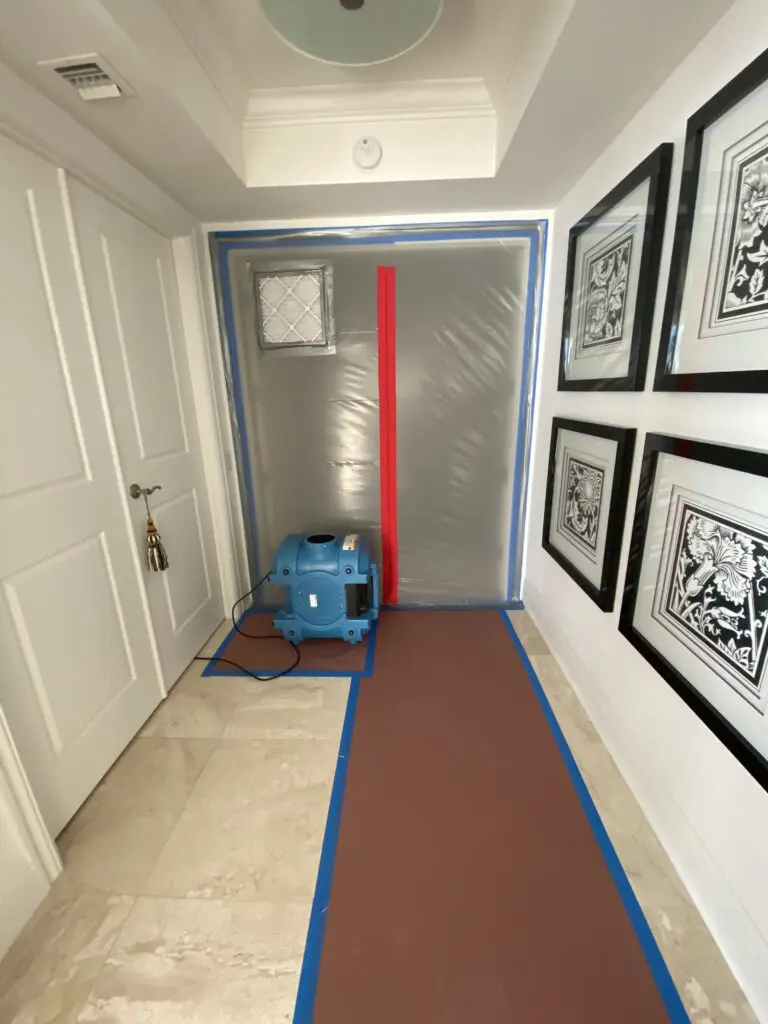 A hallway with a blue air mover and two framed pictures.