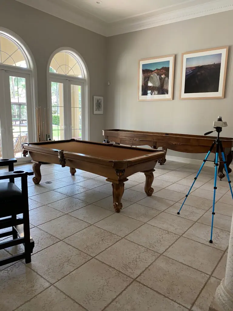 A room with two pool tables and a tripod.
