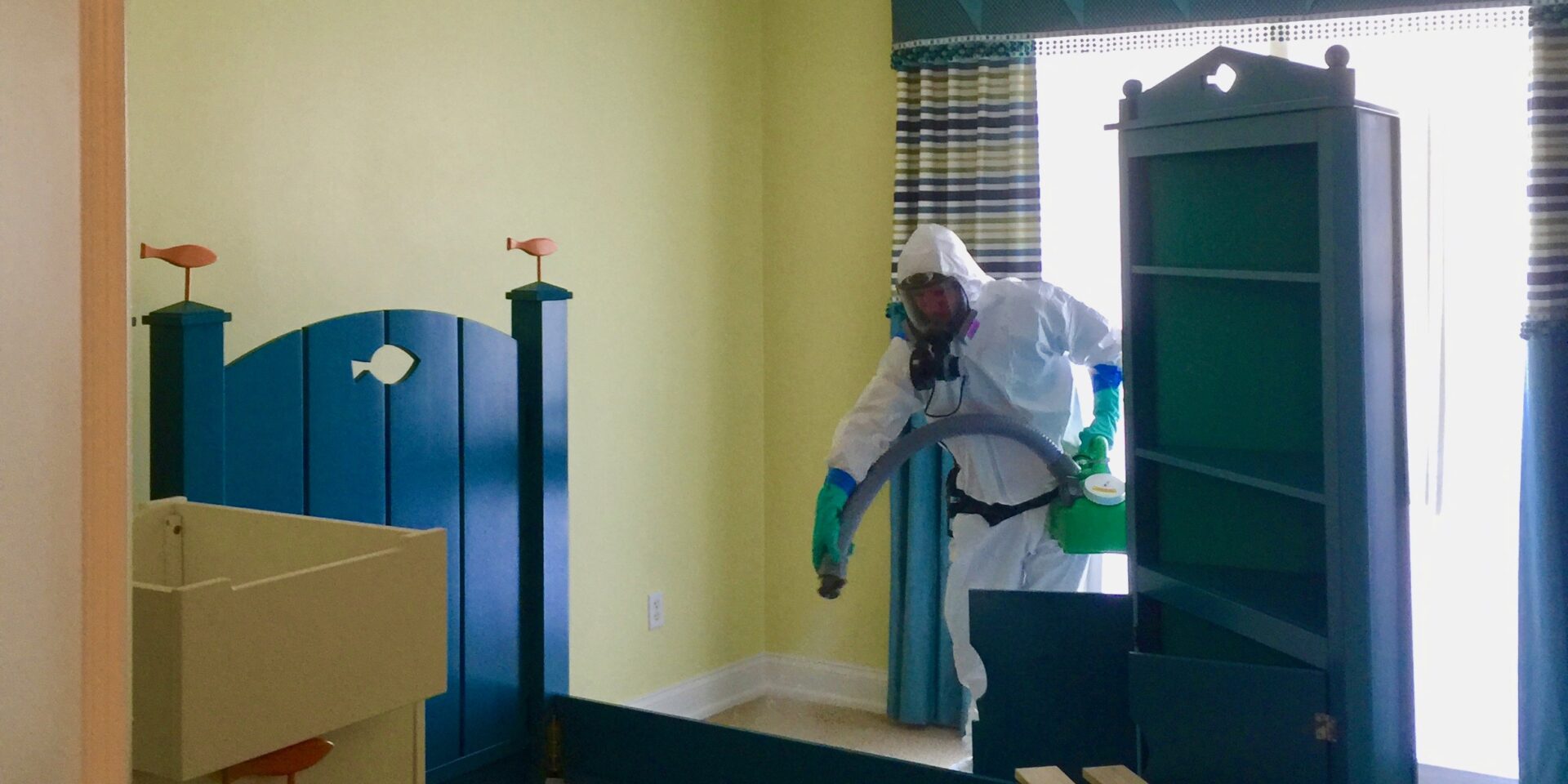 A man in white suit and green gloves cleaning.
